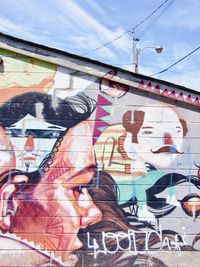 Back alley graffiti depicting a collage of several heads and faces done in different styles by different artists.