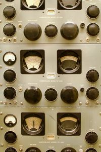 Close-up orthogonal shot of vintage radio equipment showing off various gauges, dials, knobs, and switches.