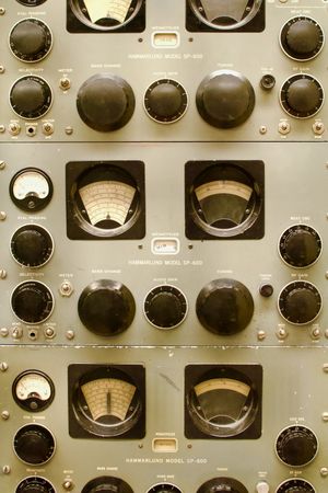 Close-up orthogonal shot of vintage radio equipment showing off various gauges, dials, knobs, and switches.