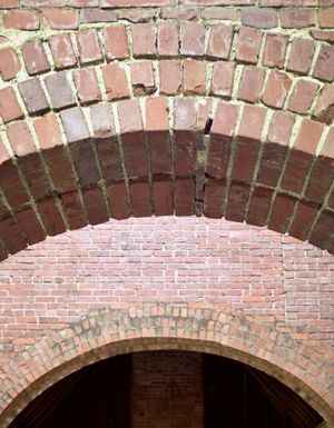 A view of two concentric red brick arches at the ruins of an old estate.