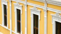 Angled view of a bright yellow colonial Central American building featuring a row of tall windows ornately framed in white.