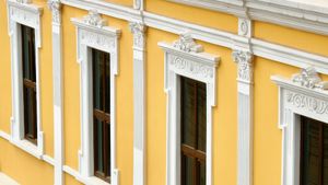 Angled view of a bright yellow colonial Central American building featuring a row of tall windows ornately framed in white.