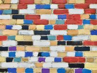 An orthogonal view of a brick wall wich each brick roughly painted in a different random color—black, white, red, blue, yellow, green, and orange.