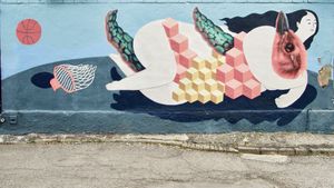 Back alley graffiti depicting a stylized naked woman wrestling a bird-like creature on an abstract basketball court.