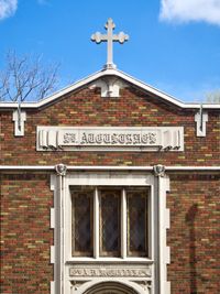 An orthogonal view of a school ornately decorated with stonework, multi-colored bricks, and—of course—a cross.
