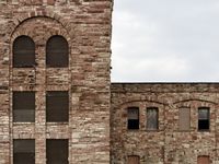 A pair of old, lonely abandoned brick buildings on a cloudy day.