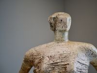 Head and shoulders shot of an abstract sculpture of a seated woman.