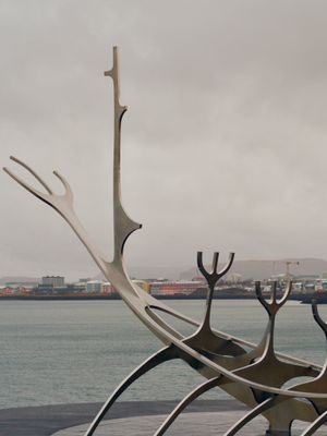 A side view of Sun Voyager, a famous art installation of a stylized viking ship made of stainless steel in Reykjavík, Iceland. Some city buildings sky can be seen in the background.