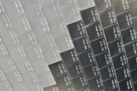 Close-up of the surface of the space shuttle, made up of individually labelled ceramic tiles. The photo is half grey tiles and half black tiles.