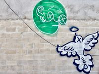 Back alley graffiti depicting a stylized green face staring at a white dove.