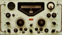 Close-up orthogonal shot of vintage radio equipment showing off various gauges, dials, knobs, and switches.