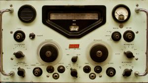 Close-up orthogonal shot of vintage radio equipment showing off various gauges, dials, knobs, and switches.