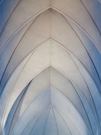 Looking up at the symmetrical arched ceiling of the famous modern church in Reykjavík, Iceland. Multiple arches branch outwards from the center of the frame.