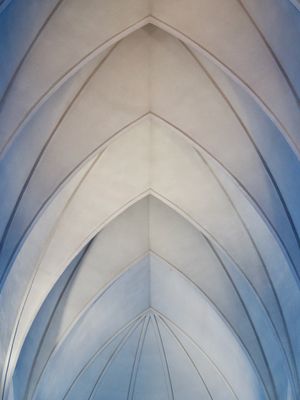 Looking up at the symmetrical arched ceiling of the famous modern church in Reykjavík, Iceland. Multiple arches branch outwards from the center of the frame.