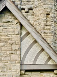 An orthogonal view of the angled roof and stone wall of an old estate.