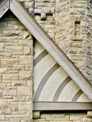 An orthogonal view of the angled roof and stone wall of an old estate.