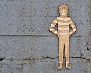 Close-up shot of a cement wall with a red and white cutout of Waldo in a parka and winter boots affixed to it.