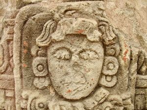 Close-up of a Mayan face carved in stone and mostly worn away over centuries.