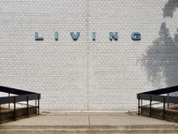 An orthogonal view of a grey wall with retro letters that spell 'LIVING' in powder blue.