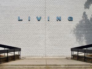 An orthogonal view of a grey wall with retro letters that spell 'LIVING' in powder blue.