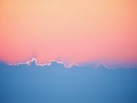 As the sun disappears behind the clouds the sky above turns a combination of orange and pink. The bottom half of the photo is the clouds contrasting in blue with the edges lit by the sun.