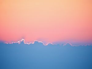 As the sun disappears behind the clouds the sky above turns a combination of orange and pink. The bottom half of the photo is the clouds contrasting in blue with the edges lit by the sun.