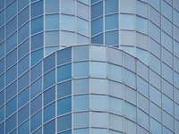 A symmetrical view looking up at the rounded corners of a glass office tower.