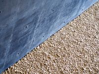 The contrast of a black concrete wall and a crushed gravel floor creates a diagonal line across the middle of the photo.