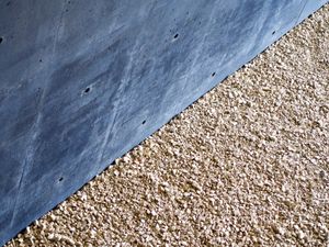 The contrast of a black concrete wall and a crushed gravel floor creates a diagonal line across the middle of the photo.