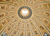 Looking up at the interior of St. Peter's dome. The decorative ceiling radiates dramatically from a circular opening in the upper third of the photo.