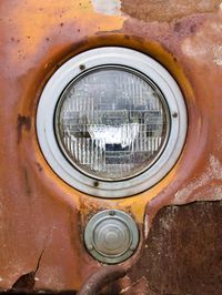 Close-up view of an abandoned truck's remaining headlight which looks to be in good conditon while surrounded by rusty, beaten metal.