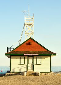 A lifeguard station on a sandy beach lit at golden hour. An observation deck on top of the cabin is tilting slightly.