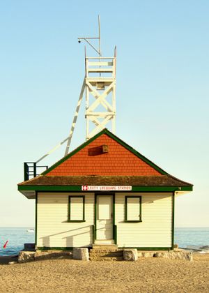 A lifeguard station on a sandy beach lit at golden hour. An observation deck on top of the cabin is tilting slightly.