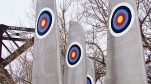 An outdoor art installation made up of airplane wings sticking up in the air with bullseyes painted on their sides.