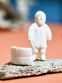 Macro shot of small stone figurine of an Inuit person holding a tool for building igloos.