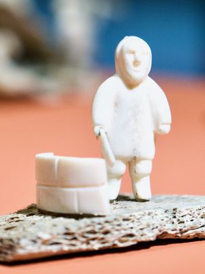 Macro shot of small stone figurine of an Inuit person holding a tool for building igloos.
