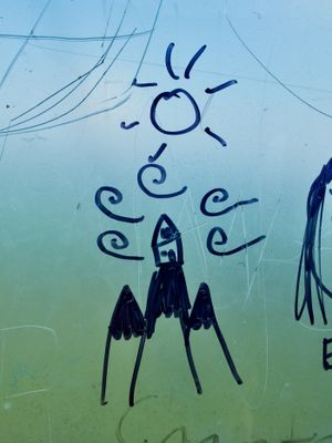 A close-up shot of mountains and wind drawn in black permanent marker on a foggy window. The outside is so blurred it forms a soft top-to-bottom gradient from blue to green.