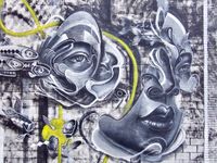 Back alley graffiti depicting a deconstructed face in grey with yellow accents.