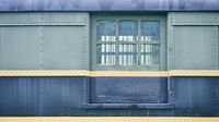 Side view of weathered, abandoned train cargo car. It's black and green with a yellow stripe along its length.