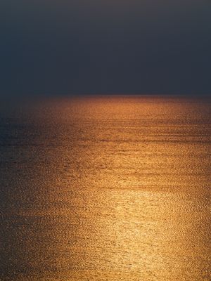 Lake Huron is lit up with golden light while the sky in the background is an ominous dark grey.