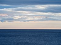 Numerous cloud banks coalesce over the horizon of a deep, dark blue Lake Huron.